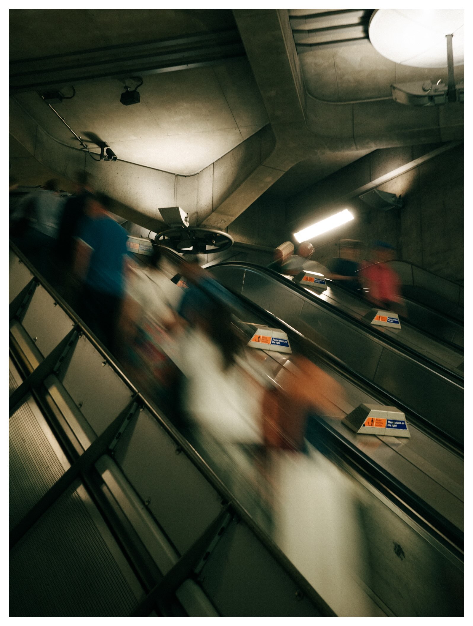 Commuters blurred in motion on escalators at Westminster Underground